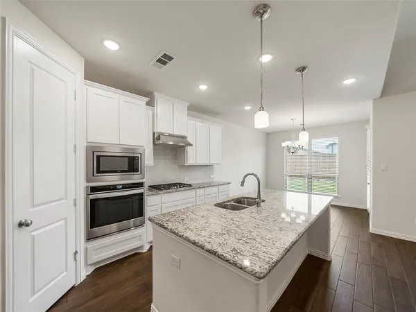 a kitchen with stainless steel appliances granite countertop a sink a stove and a wooden floors