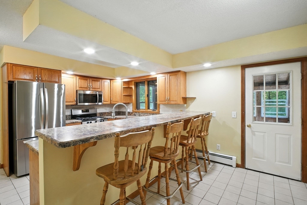 164 Wales Road Monson, MA 01057 - Photo 9 of 41 a kitchen with granite countertop a table chairs microwave and refrigerator
