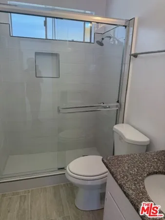 a bathroom with a granite countertop toilet and a shower