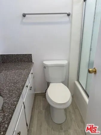 a bathroom with a granite countertop toilet and a sink