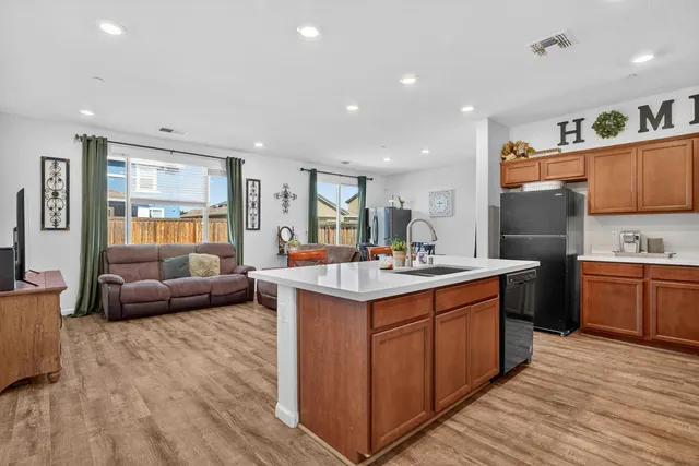 a kitchen with kitchen island granite countertop a sink and a stove top oven with wooden floor