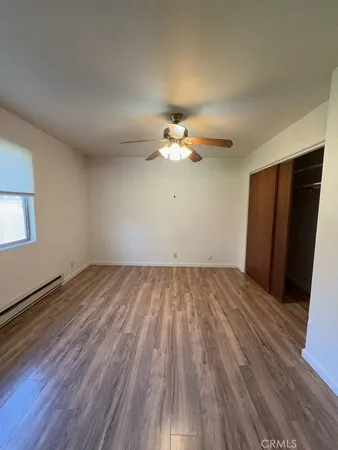 an empty room with wooden floor chandelier fan and windows
