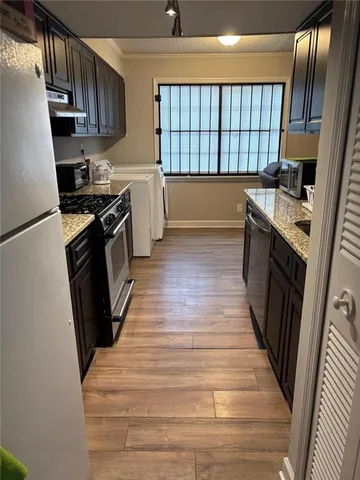 a kitchen with granite countertop a sink a stove wooden floor and cabinets