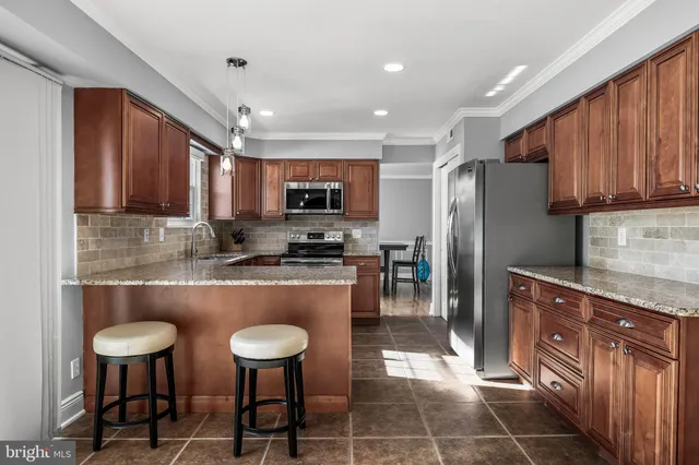 a kitchen with stainless steel appliances granite countertop a table chairs sink refrigerator and microwave