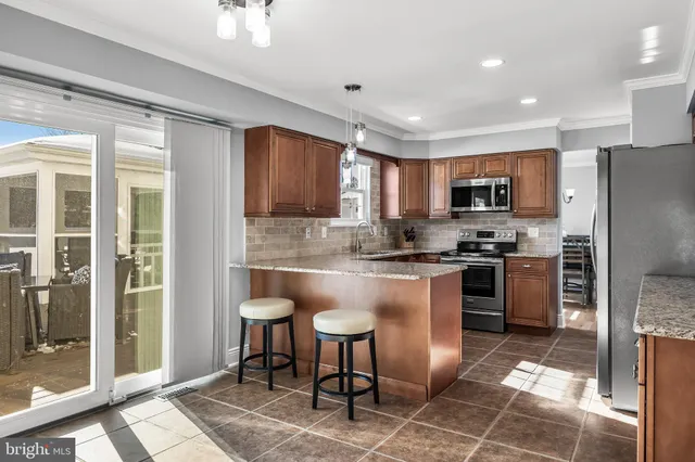 a kitchen with stainless steel appliances granite countertop a refrigerator a stove a sink a dining table and chairs