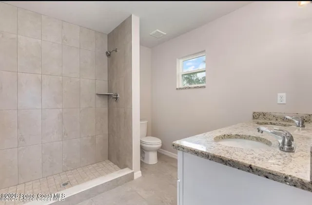a bathroom with a granite countertop sink a toilet and a shower