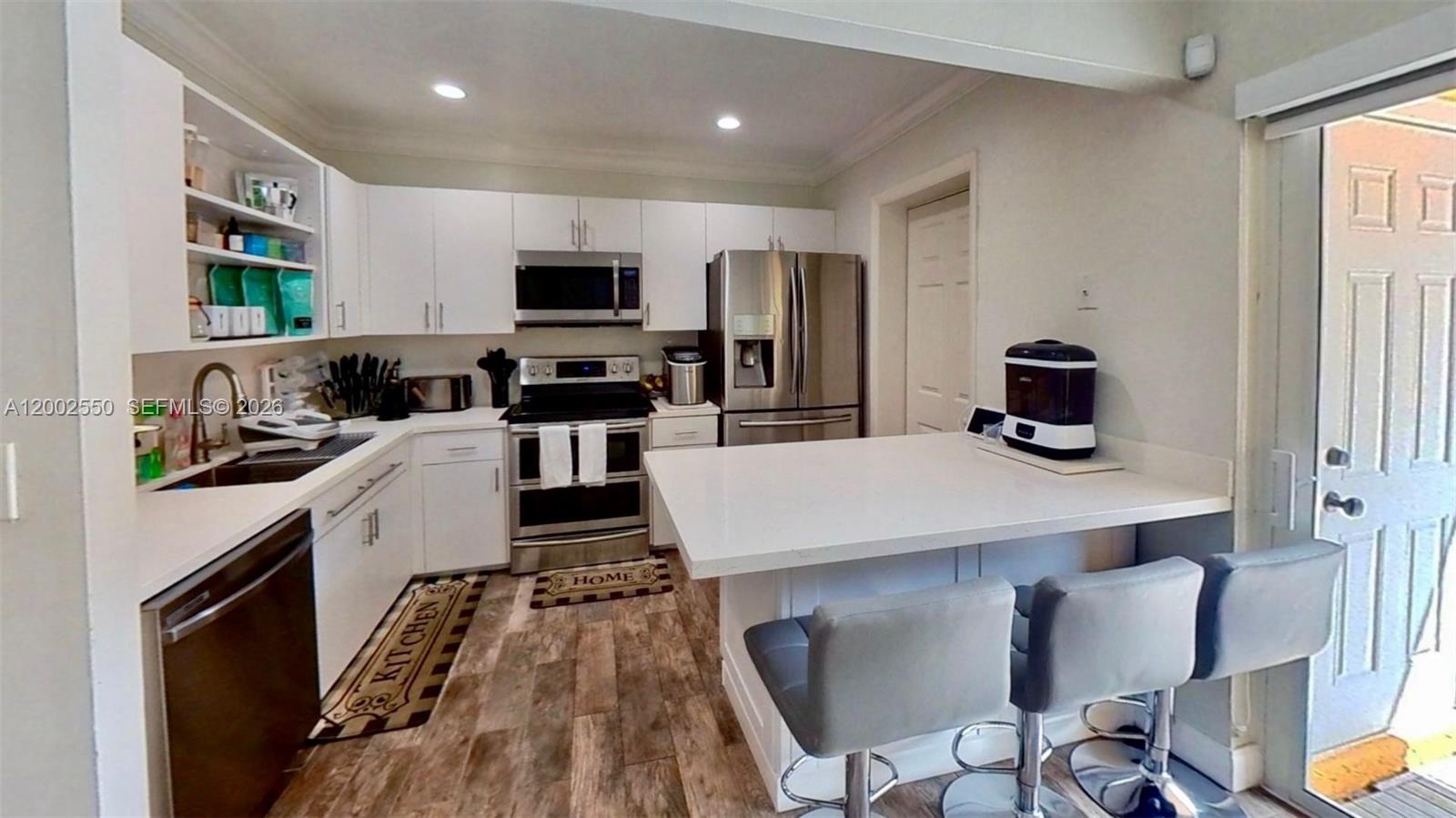 13731 Southwest 84th Street, Unit C11 Miami, FL 33143 - Photo 6 of 32 a kitchen with stainless steel appliances a stove a sink a microwave a refrigerator cabinets and a dining table
