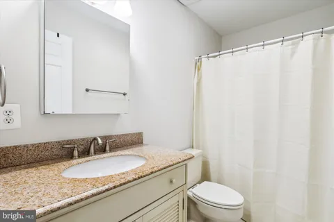 a bathroom with a granite countertop sink toilet and a mirror