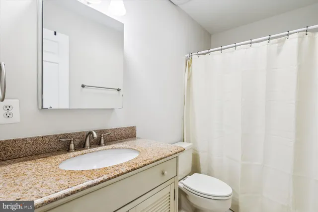 a bathroom with a granite countertop sink toilet and a mirror