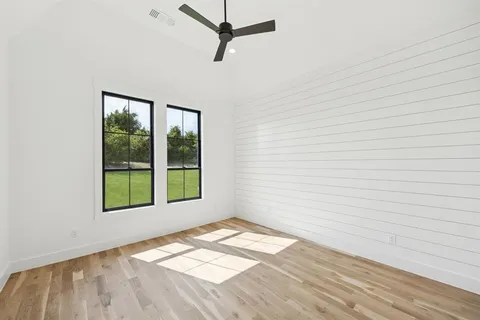 a view of an empty room with a window and wooden floor