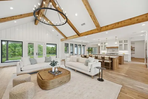 a living room with furniture a floor to ceiling window and wooden floor