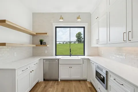 a kitchen with white cabinets window and sink