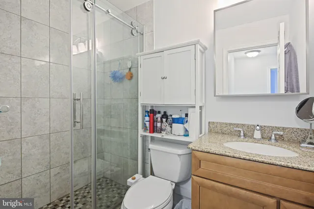 a bathroom with a granite countertop sink toilet and shower