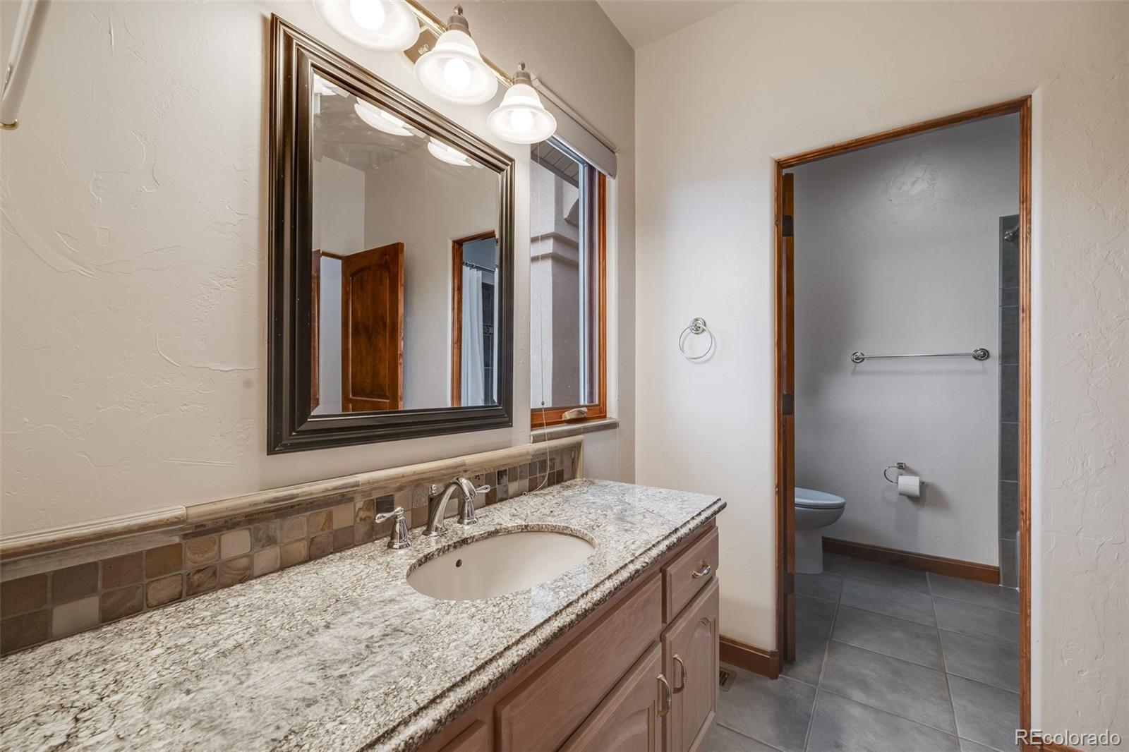 185 River Ridge Trail Walsenburg, CO 81089 - Photo 29 of 50 a bathroom with a granite countertop sink and a mirror