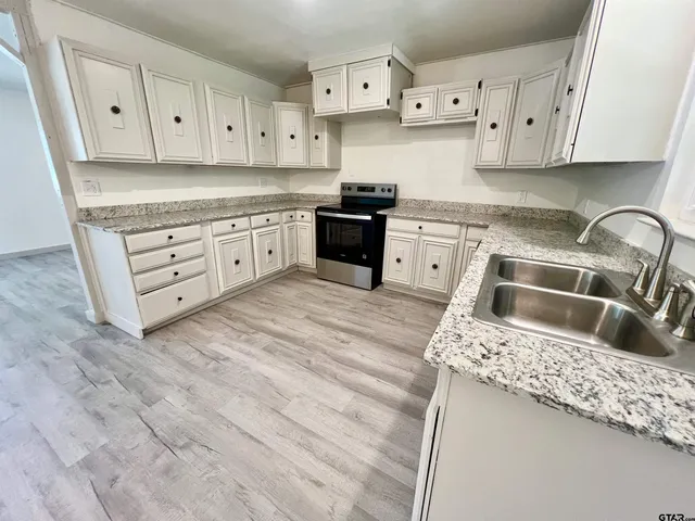 a kitchen with granite countertop white cabinets and stainless steel appliances