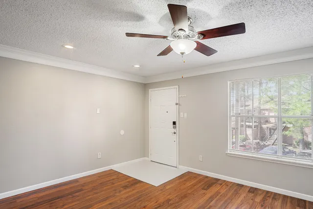 an empty room with wooden floor chandelier and windows