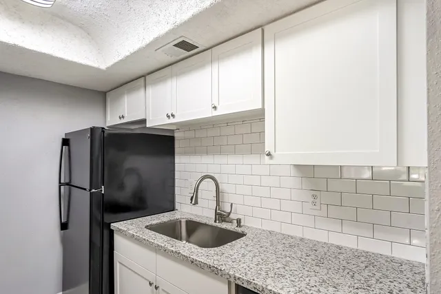 a bathroom with a granite countertop bathtub shower sink vanity and toilet