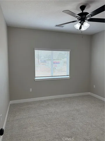an empty room with a window and a fan