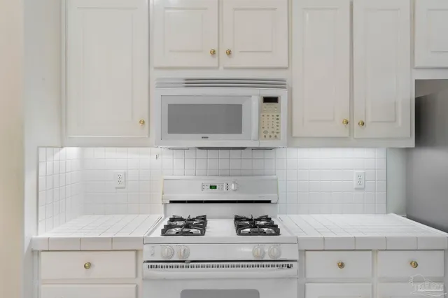 a kitchen with white cabinets and appliances