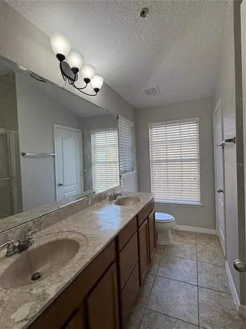 a bathroom with a granite countertop sink a toilet and mirror
