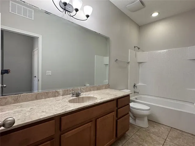 a bathroom with a granite countertop sink a toilet a mirror and shower