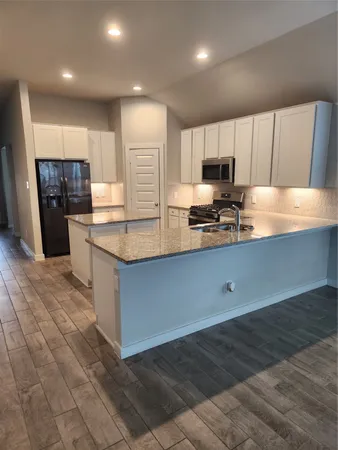 a kitchen with stainless steel appliances granite countertop a sink a stove and a refrigerator