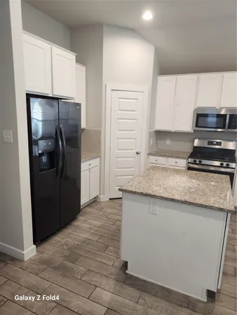 a kitchen with granite countertop a refrigerator and a stove