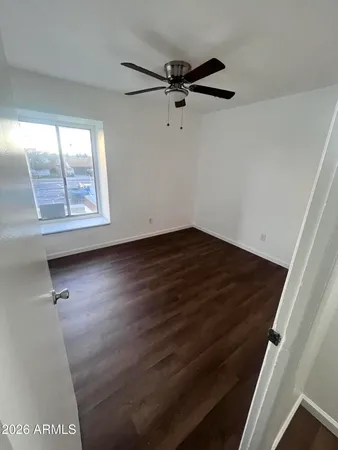 an empty room with wooden floor fan and windows