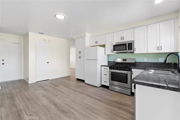a kitchen with granite countertop a refrigerator stove top oven and sink