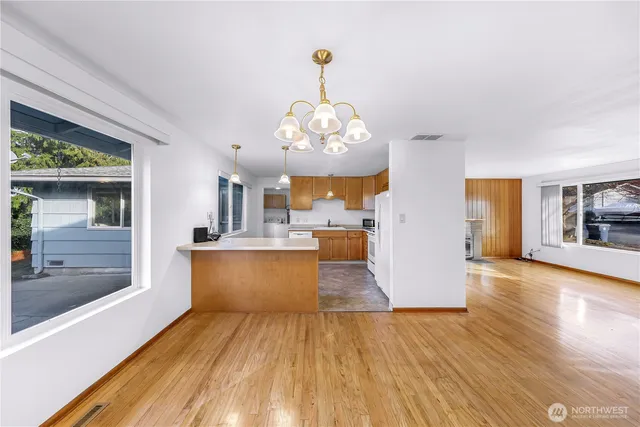 a view of a kitchen with kitchen island a sink wooden floor and a large window