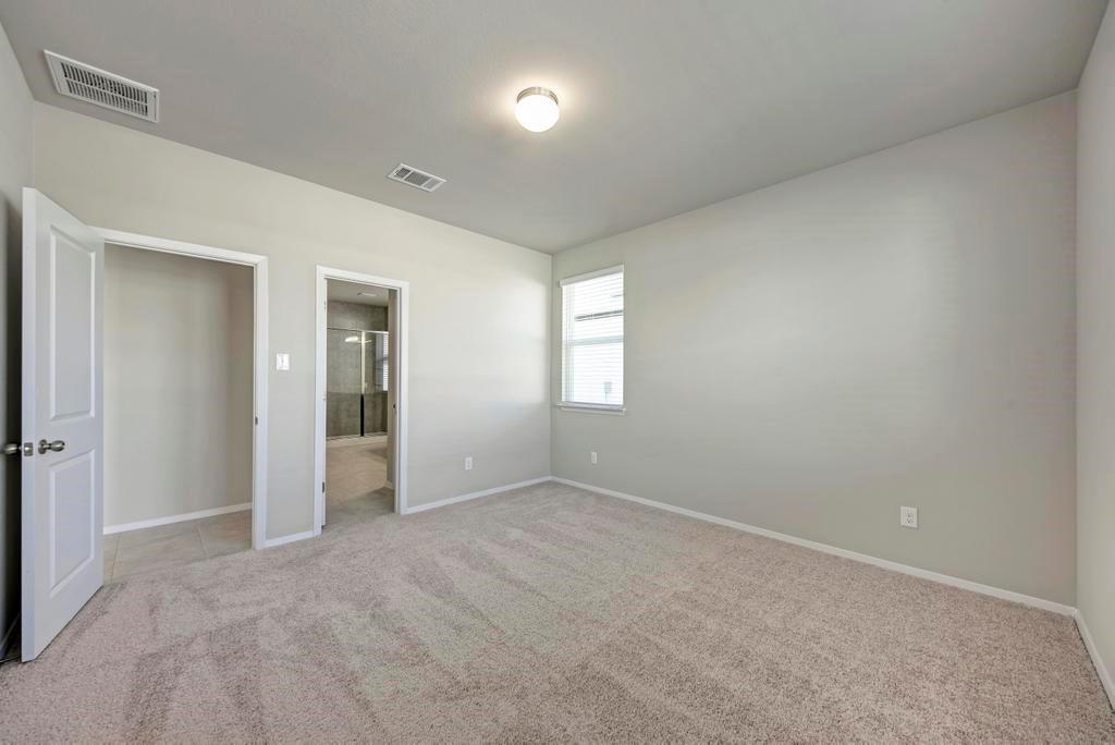 1209 Goforth Road Kyle, TX 78640 - Photo 16 of 32 A spacious primary bedroom with plush carpet and a well-lit window.