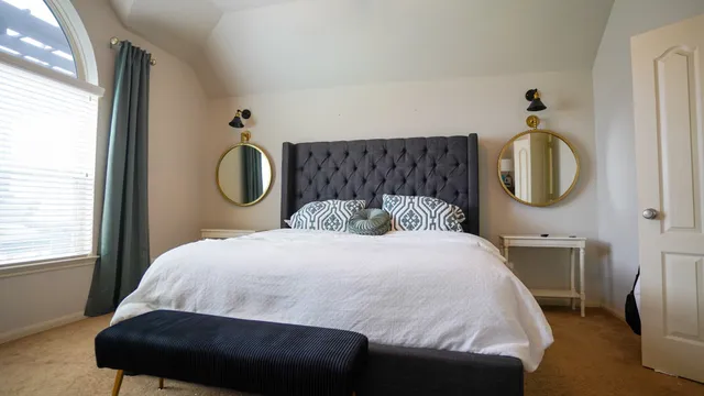 a bedroom with a bed a mirror and a window