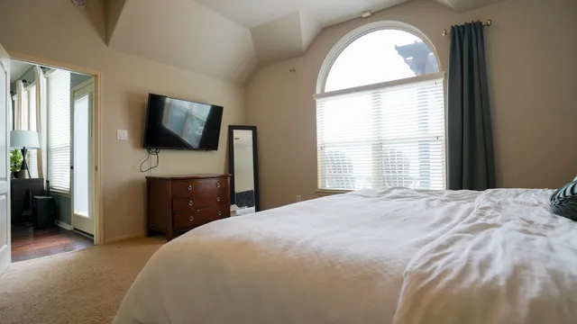 a bedroom with a bed and a flat tv screen on dresser