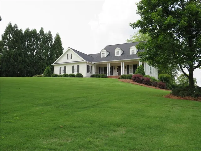 a front view of a house with a garden and trees