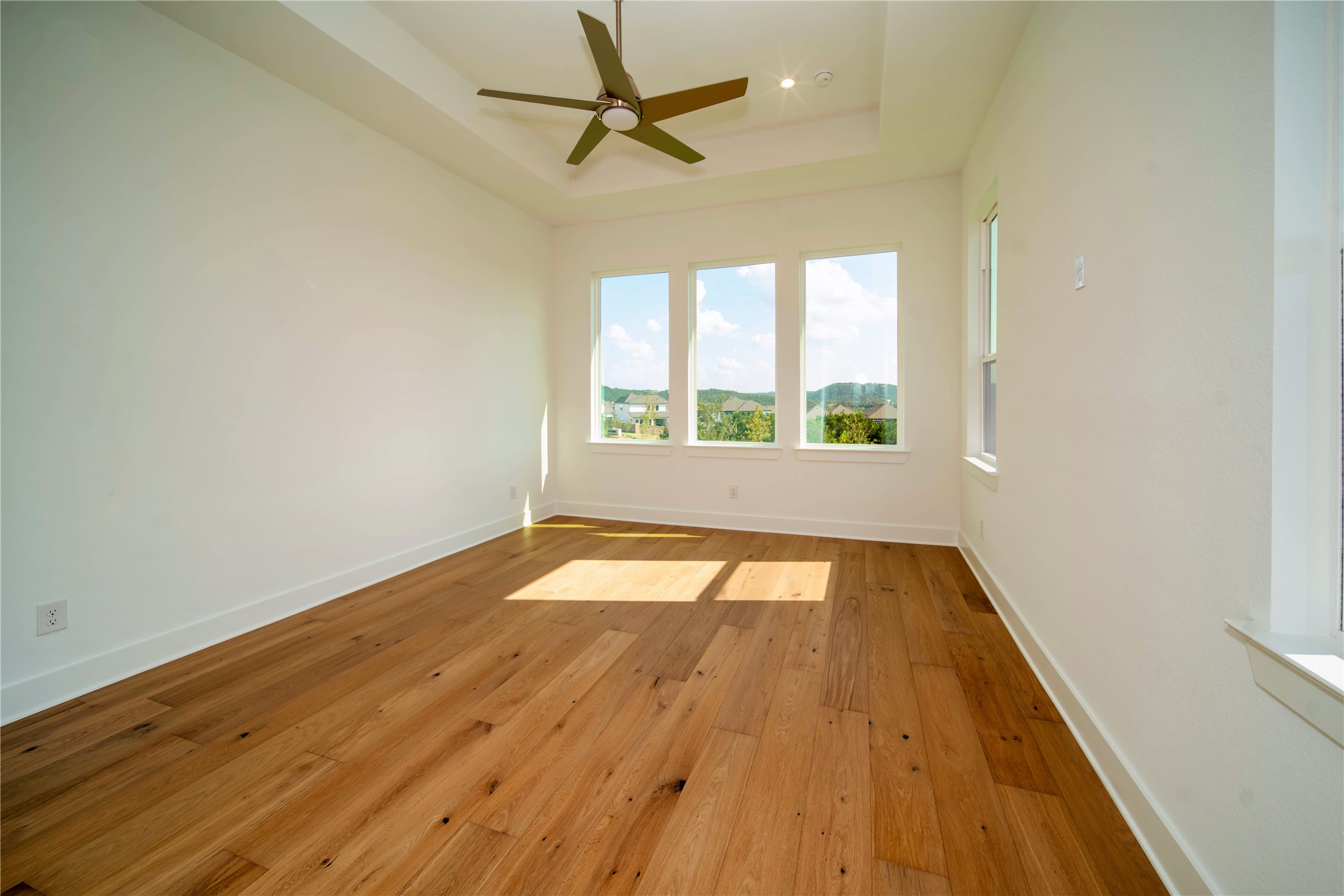 2029 Varese Path Leander, TX 78641 - Photo 11 of 32 an empty room with wooden floor fan and windows