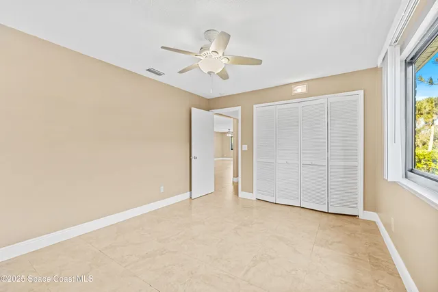 an empty room with windows and fan