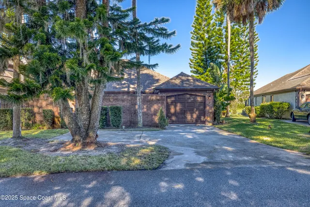 a front view of a house with garden and trees