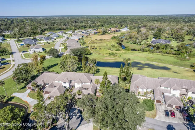 an aerial view of residential houses with outdoor space and trees