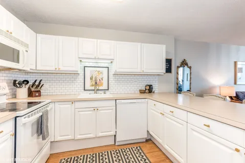 a kitchen with a sink dishwasher stove and white cabinets
