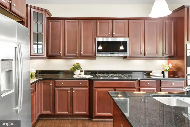 a kitchen with stainless steel appliances granite countertop a refrigerator a sink a stove a kitchen island and cabinets