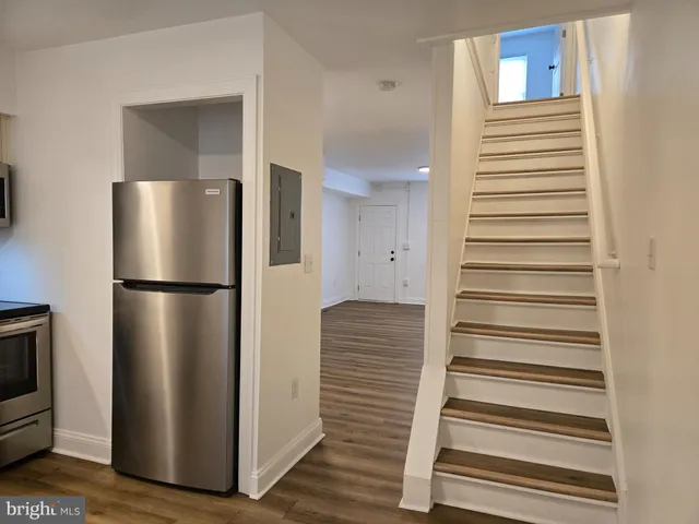 a view of a kitchen with refrigerator and wooden floor