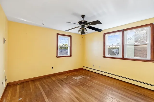 a view of an empty room with a window and wooden floor