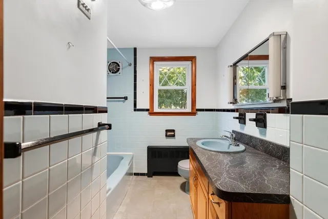 a bathroom with a granite countertop sink a mirror and a bathtub