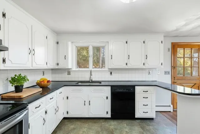a kitchen with white cabinets and a window