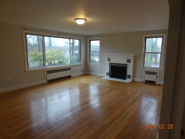 wooden floor fireplace and windows in an empty room