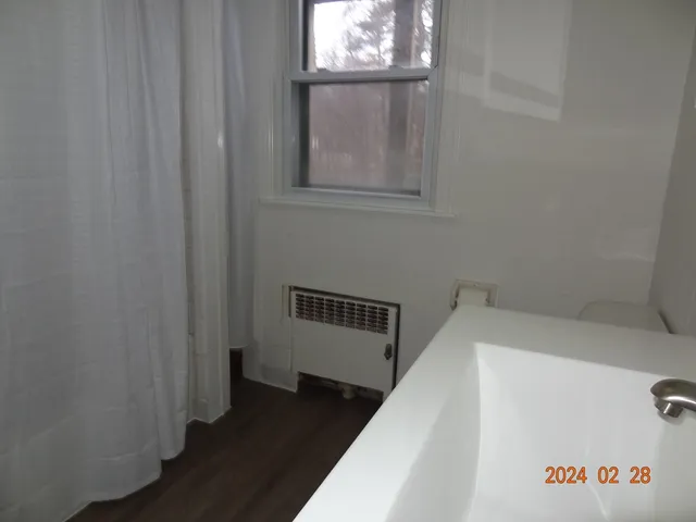 a view of hallway with window and wooden floor