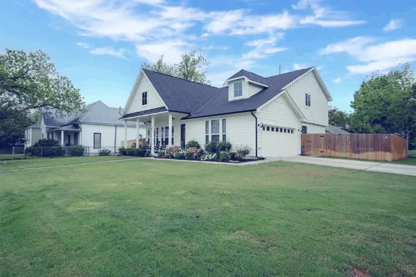 a view of a house with a big yard and large tree