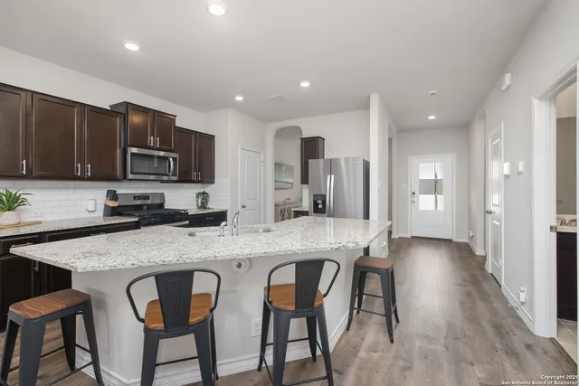 a kitchen with stainless steel appliances granite countertop a stove a sink a microwave a refrigerator and cabinets