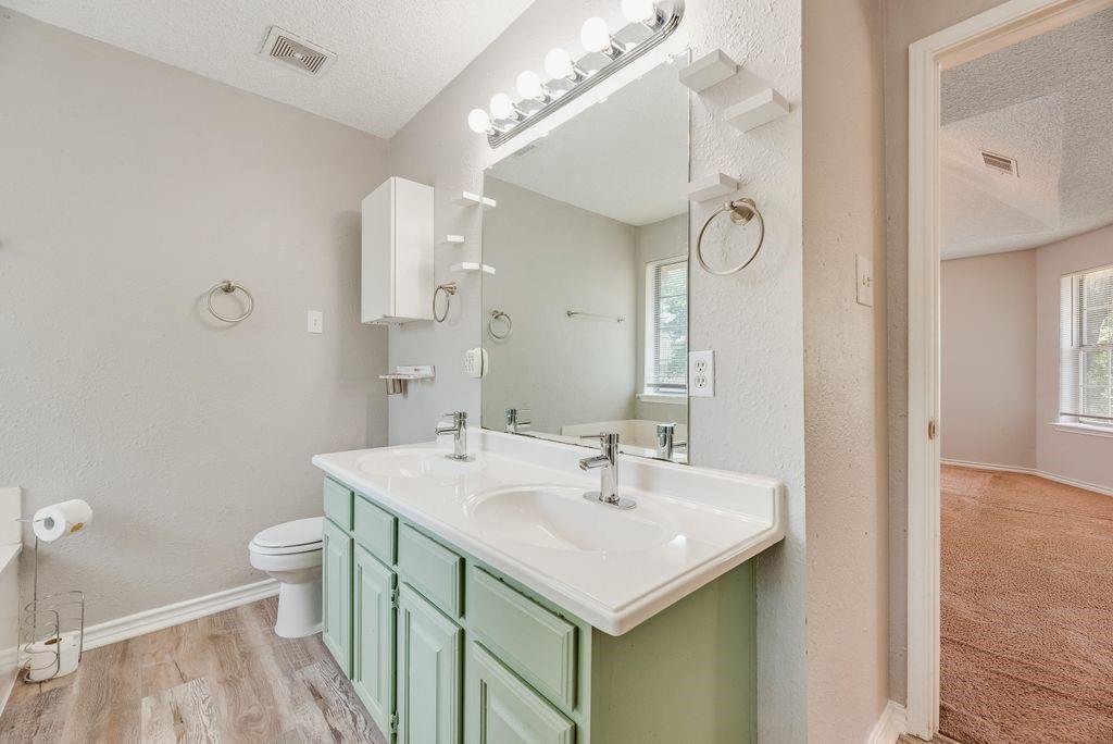 5610 Eagle Rock Road Arlington, TX 76017 - Photo 22 of 33 Bathroom featuring a double vanity with light green cabinetry and integrated white sinks