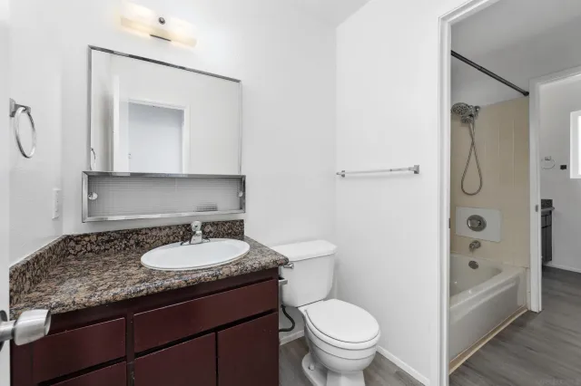 a bathroom with a granite countertop sink toilet and shower